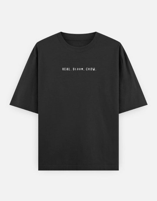 Front view of The Unserious Studio oversized unisex tee featuring a heal, bloom, glow graphic design on a soft, relaxed fit shirt.