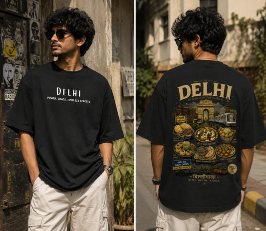 A man wearing a black DELHI graphic T-shirt is shown in a split front-and-back view. The front has white text reading 'DELHI' and smaller 'POWER CARGO TIMELESS STREETS', while the back features a large multicolor Delhi city and food illustration with 'DELHI' in gold at the top.