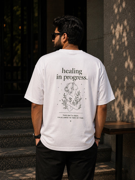 Man wearing a white t-shirt with 'healing in progress' text and graphic, standing outdoors.