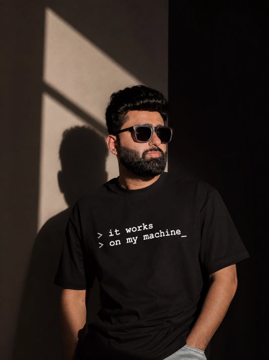 Man wearing a black t-shirt with text, standing against a dark background
