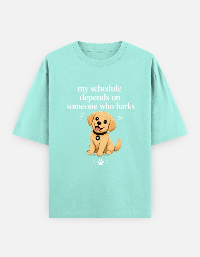 Front view of The Unserious Studio unisex oversized tee featuring bold text: "My Schedule Depends on Someone Who Barks."