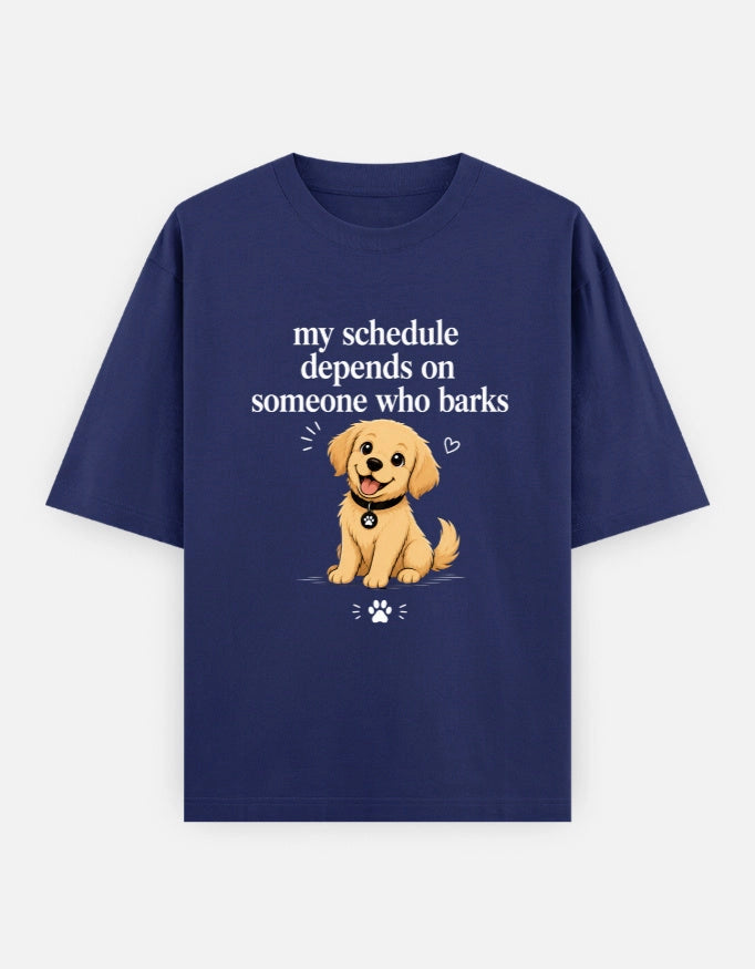 Unisex oversized T-shirt by The Unserious Studio, featuring a front graphic with the phrase "My Schedule Depends on Someone Who Barks."