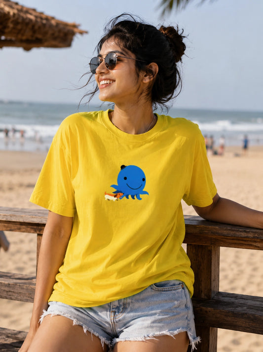 Woman wearing a yellow t-shirt with a blue octopus design on a beach.