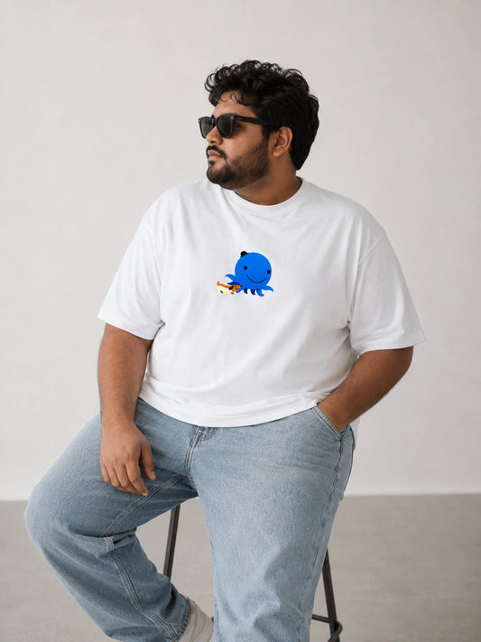 A man wearing a white short-sleeve t-shirt with a blue cartoon octopus graphic on the chest, paired with light blue jeans and black sunglasses, sitting on a stool against a plain light gray wall.