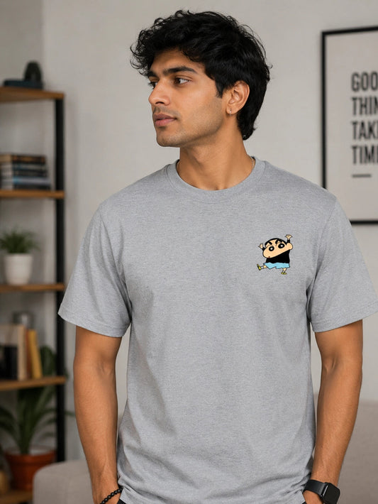 Man wearing a gray t-shirt with a small graphic of Shinchan on the chest in a living room.